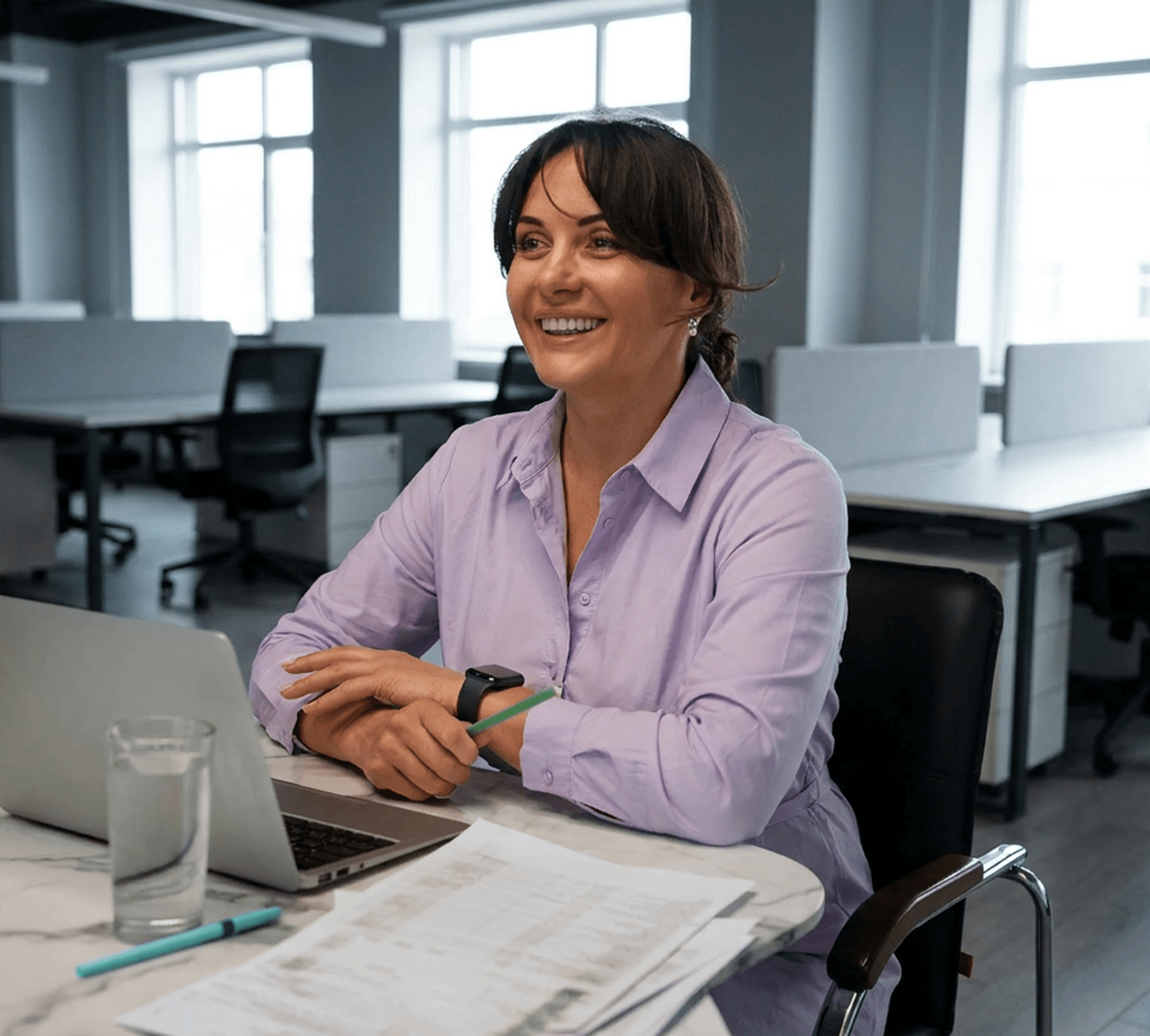 Colaboradora sorrindo em escritório usando laptop
